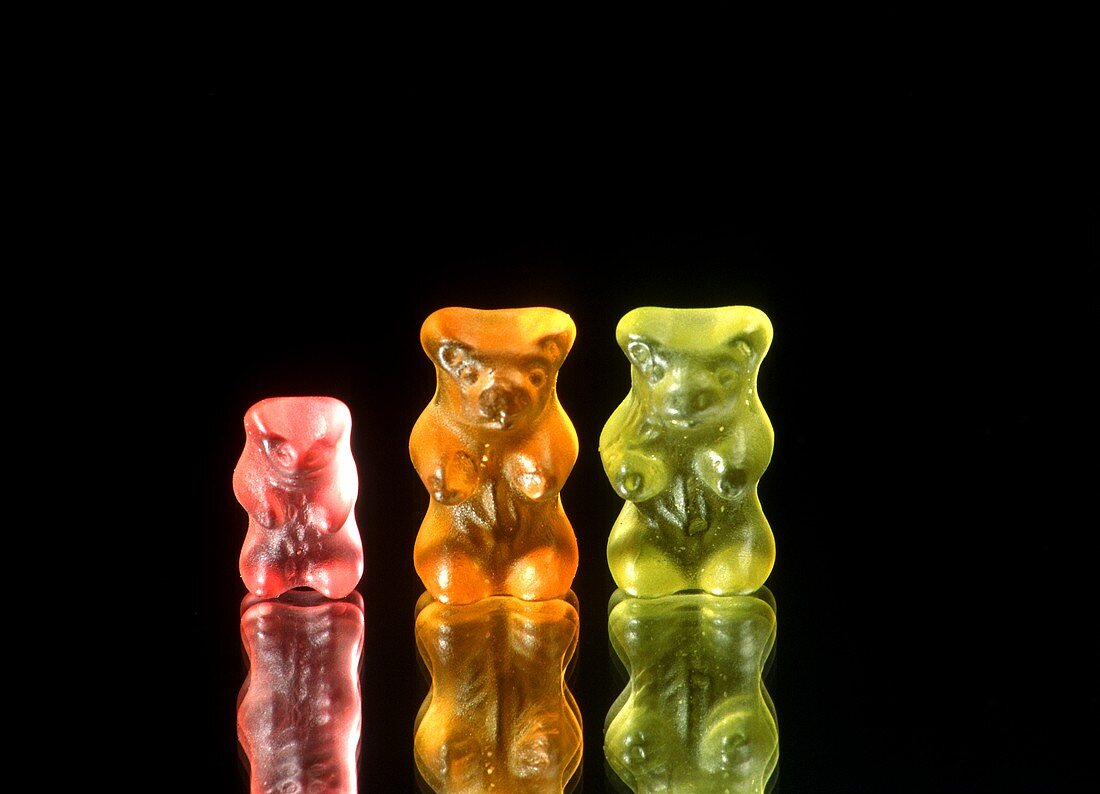 Three gummi bears against black background
