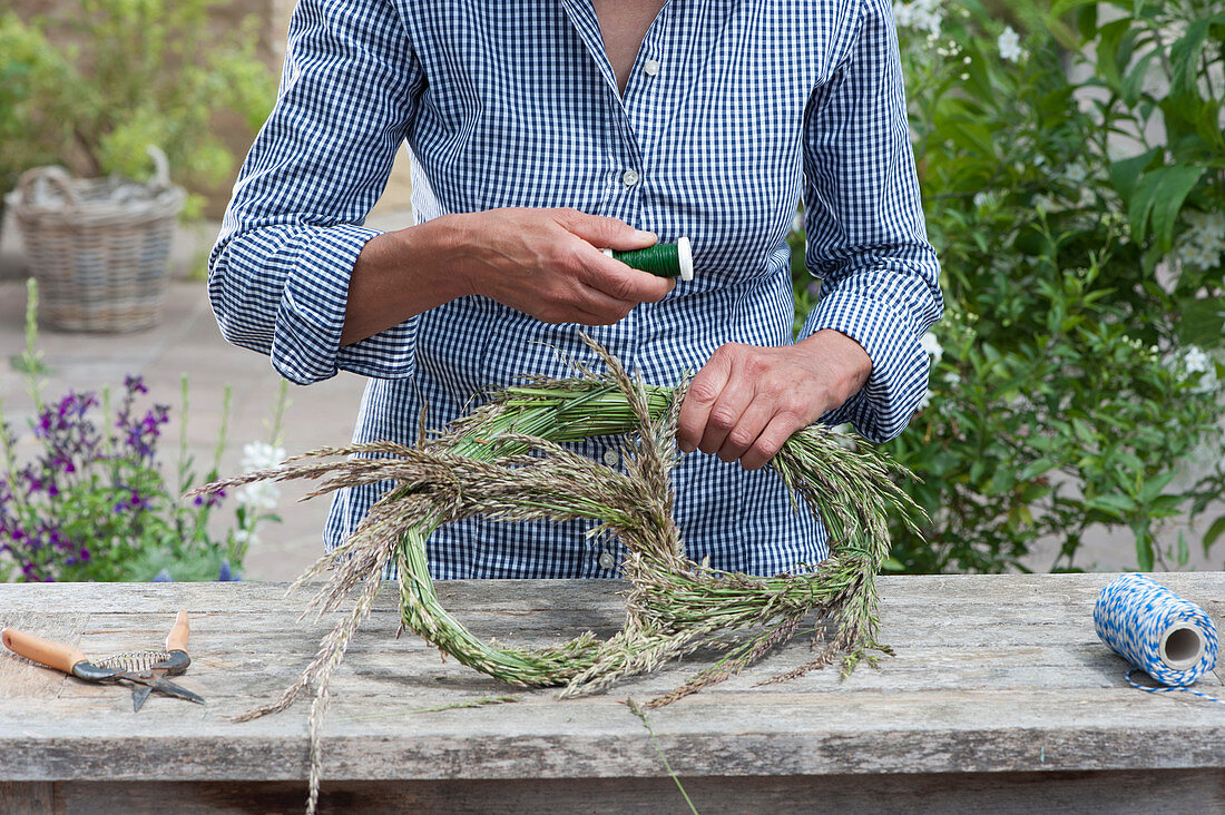 Tying a giant pretzel made of grass Woman bends a bundle of grass stiffened and wrapped in pretzel shape and fixed with winding wire