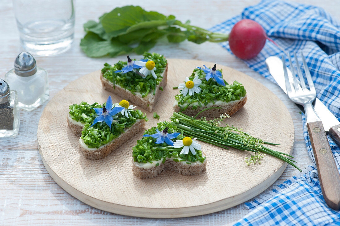 Small snack plate with heart-shaped bread with butter, chives and borage and chamomile flowers
