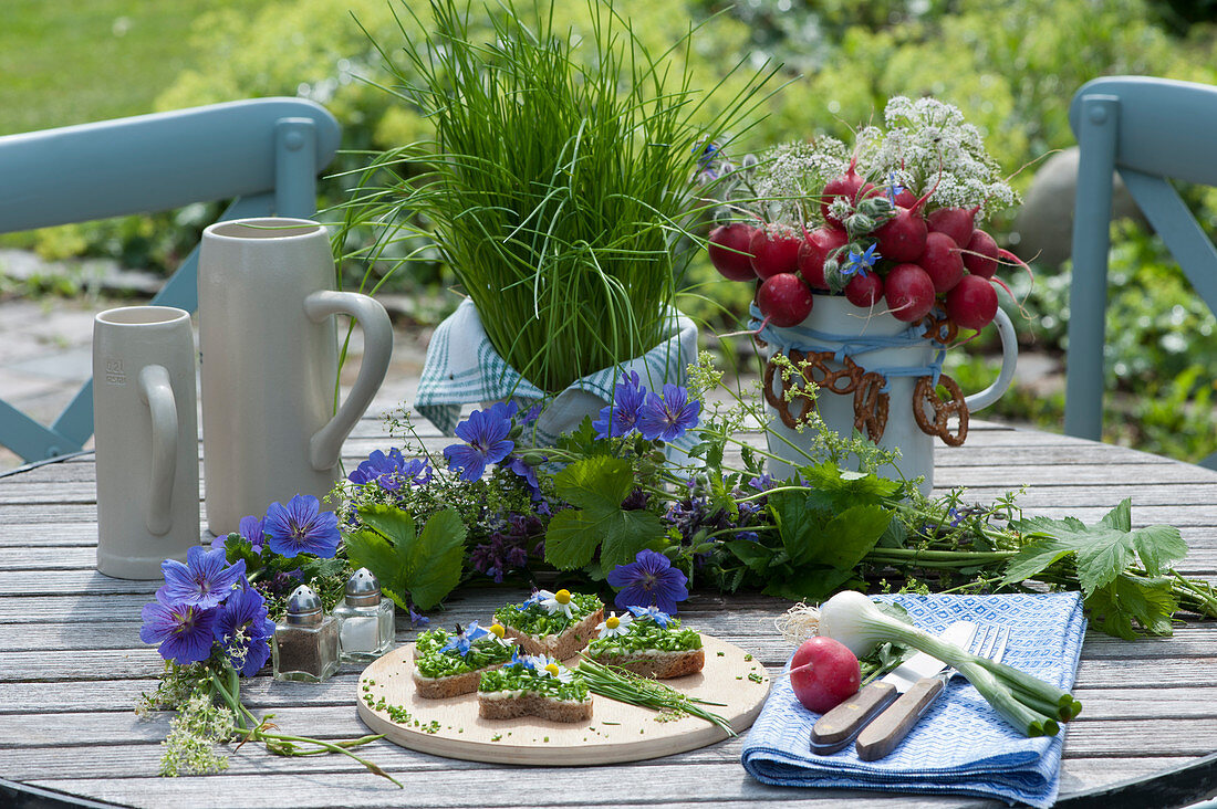 Edible bouquet of radishes, borage and beaverelle, decorated with pretzels, a pot with chives, garland of cranesbills, hops and bedstraw