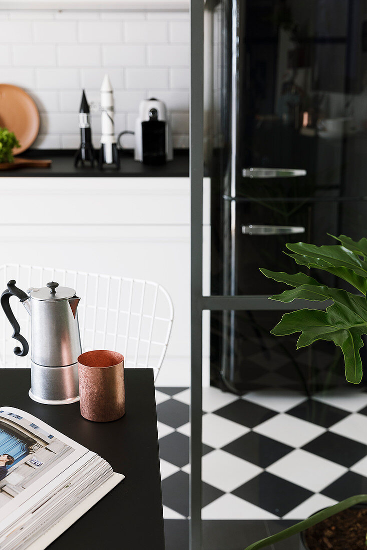 Espresso pot and copper beaker on dining table in kitchen