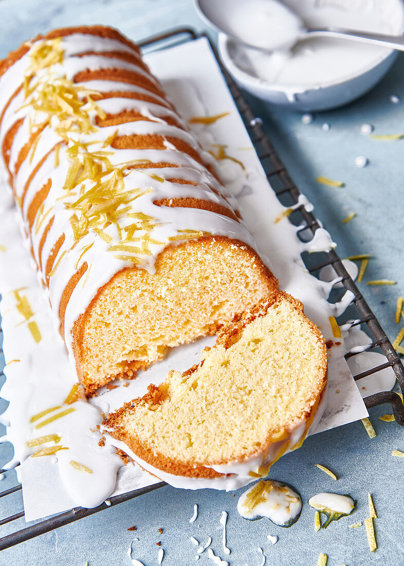 Lemon cake, a piece cut, on white baking paper