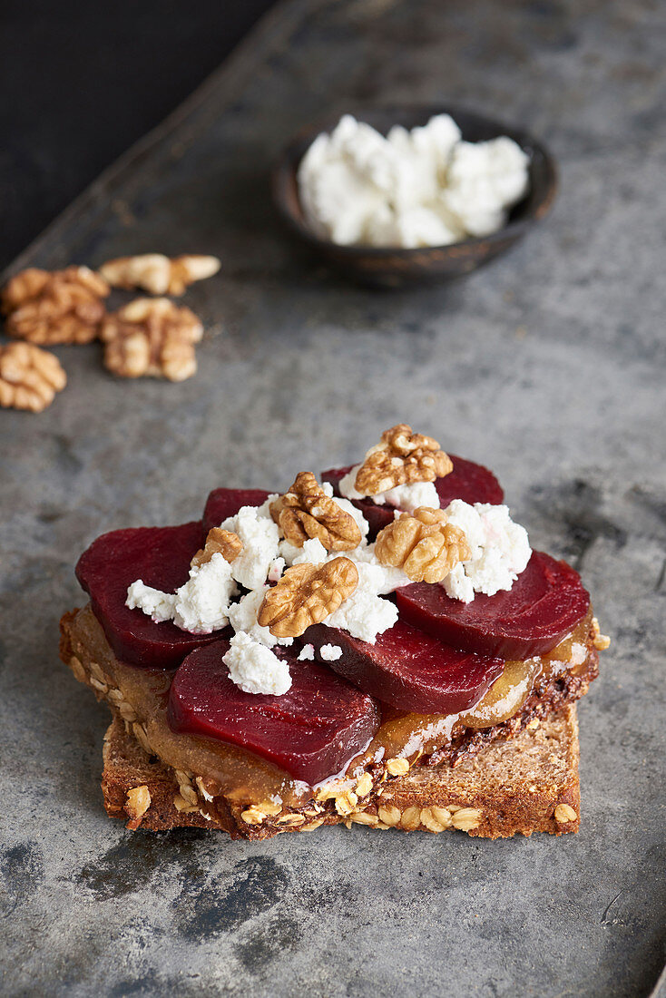 Two slices of whole grain bread with honey, beetroot, fresh goat cheese and walnuts