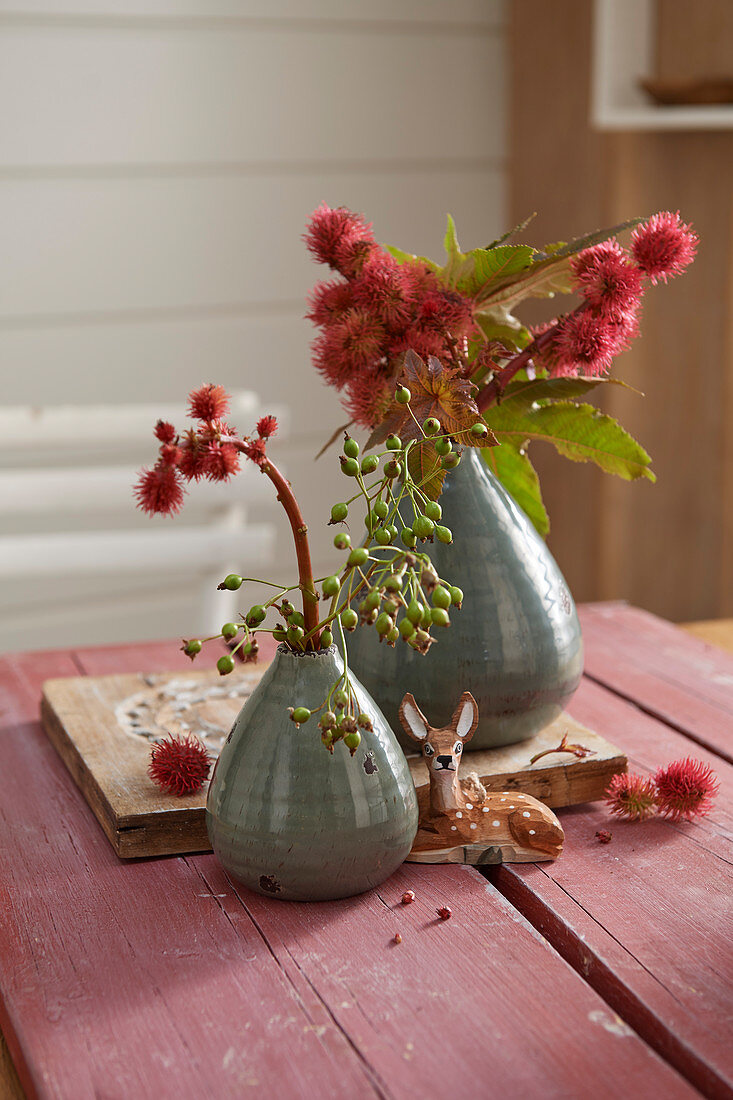 Zweige mit roten Blüten in Vasen und Rehfigur