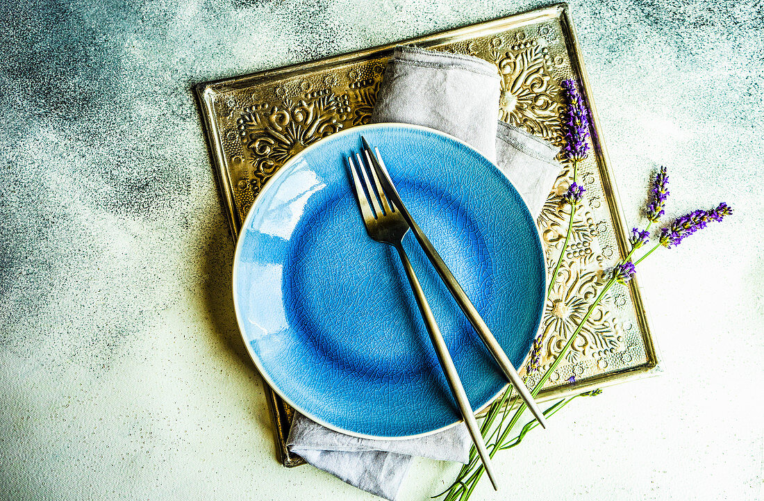 Sommerliches Gedeck mit blauem Teller, Besteck und frischen Lavendelblüten