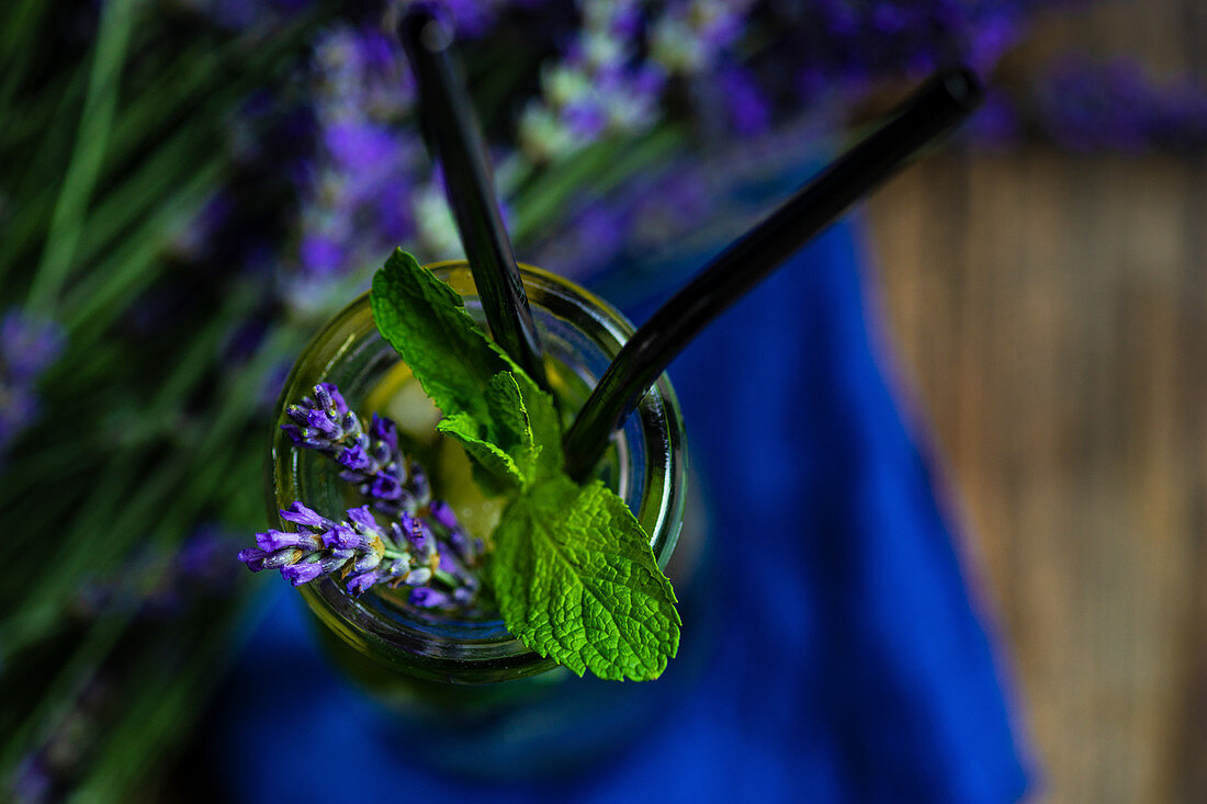 Summer detox lemonade with lavender, lemon and mint in vintage glass with straw on rustic background with copy space