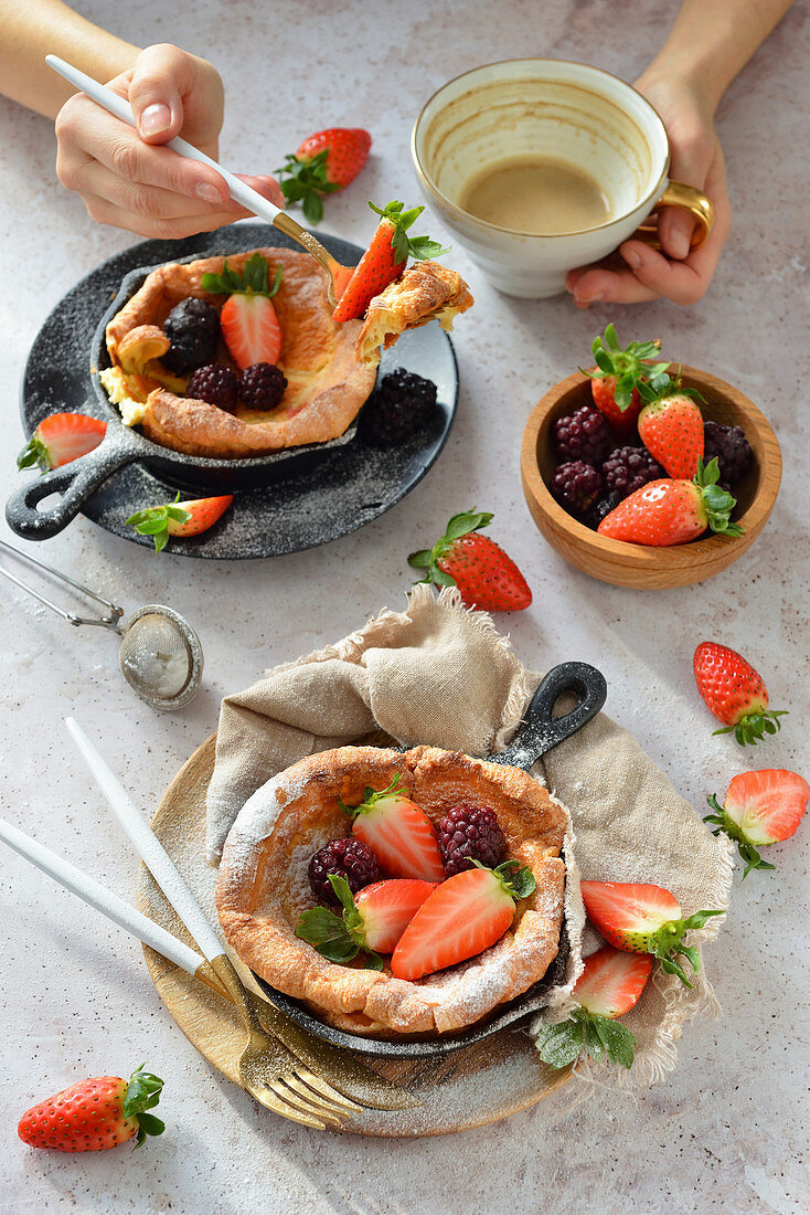 Dutch baby pancakes with strawberries and blackberries coffee mug hands