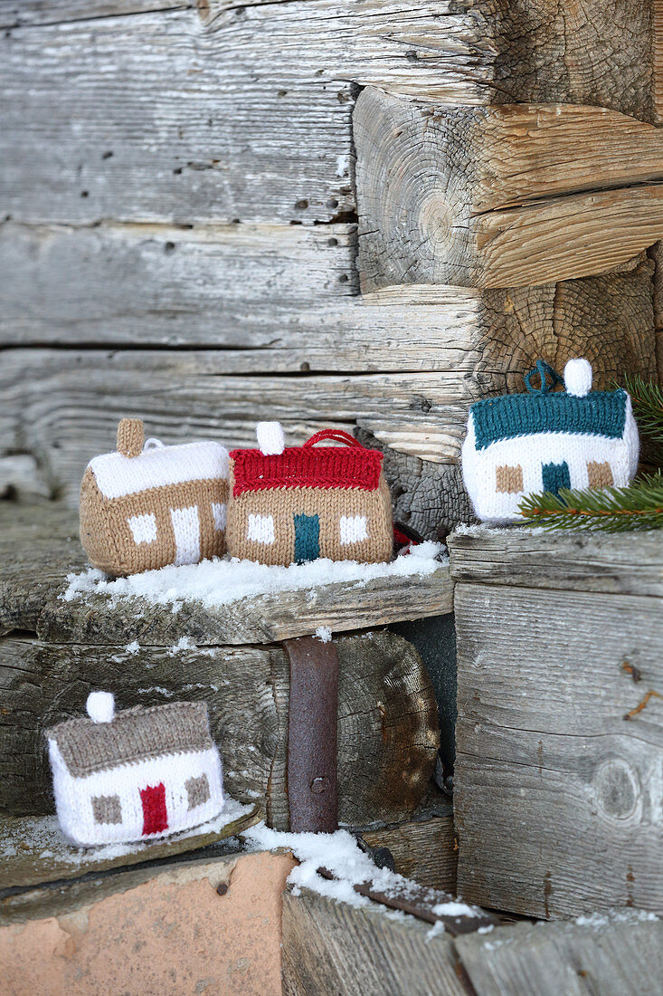 Knitted winter decorations in shapes of houses on snowy wood
