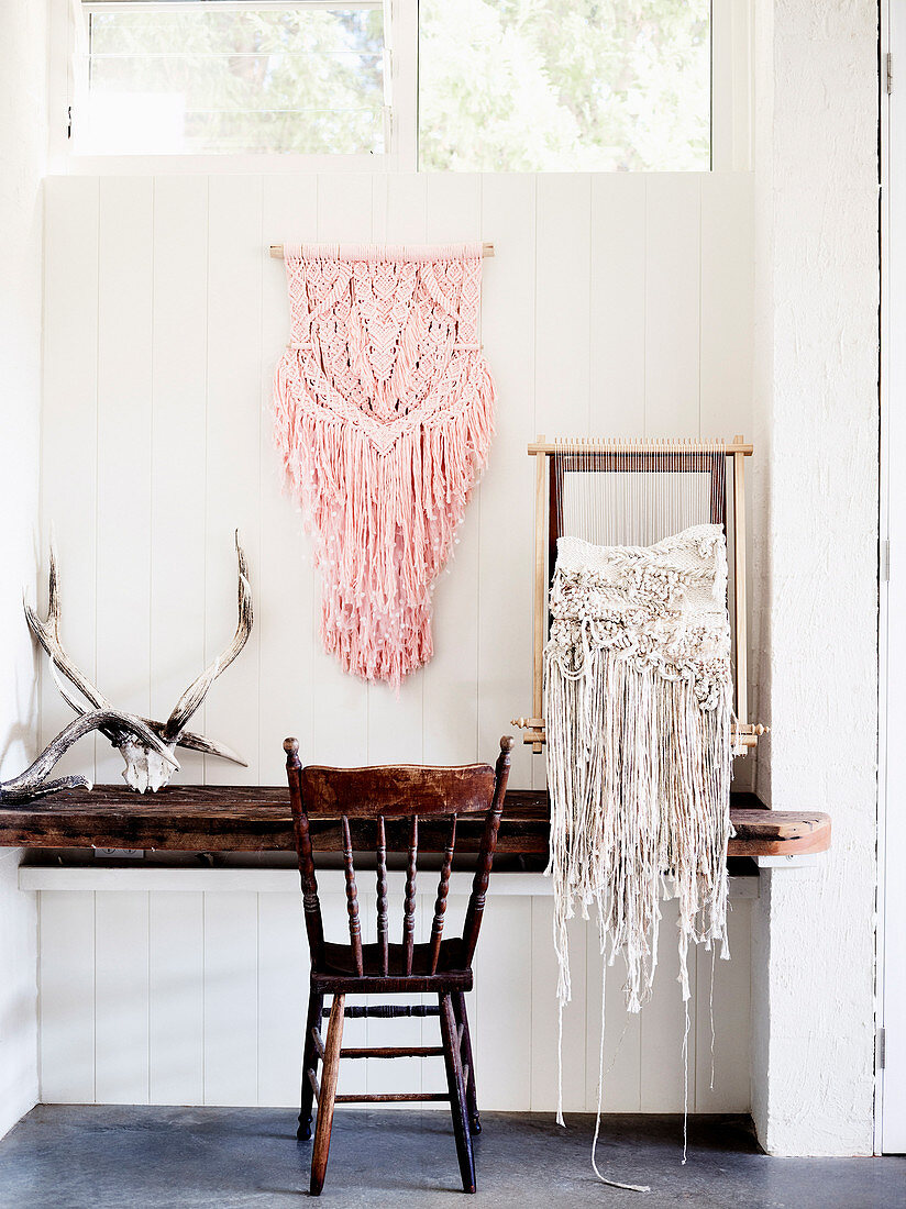 Macramé on the wall and weaving frame on rustic wooden table