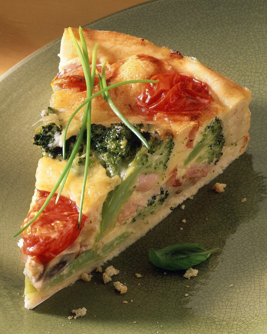 A piece of broccoli and tomato quiche with bacon