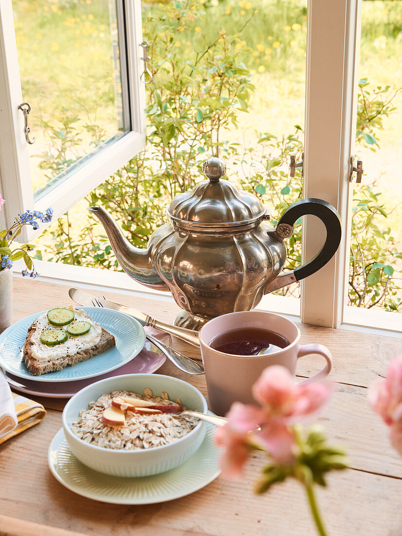 Breakfast with tea, porridge and bread by an open window