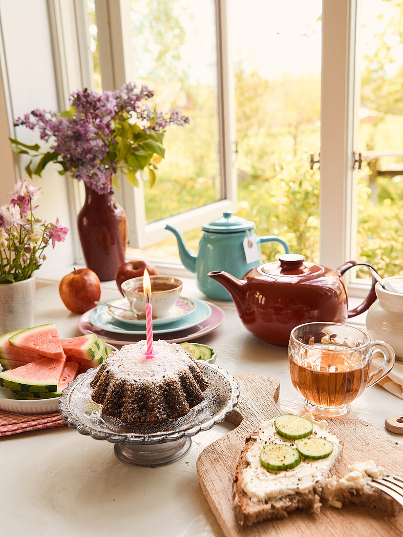 Teatime am geöffneten Fenster mit Brot, Kuchen und Obst