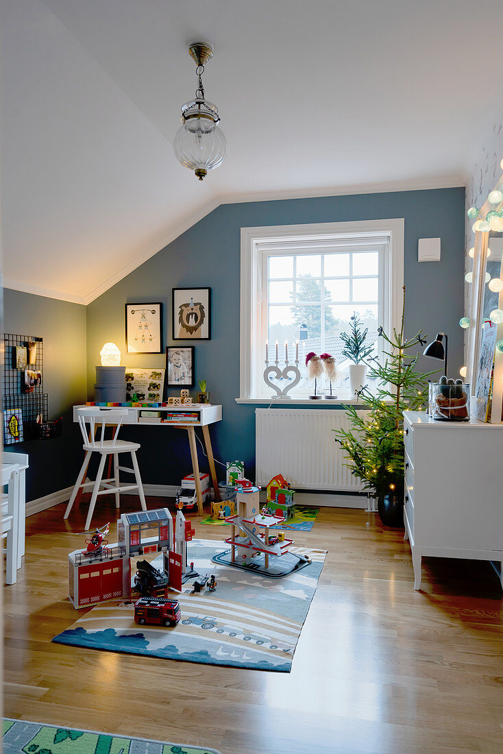 Christmas tree in child's bedroom with blue walls and sloping ceiling