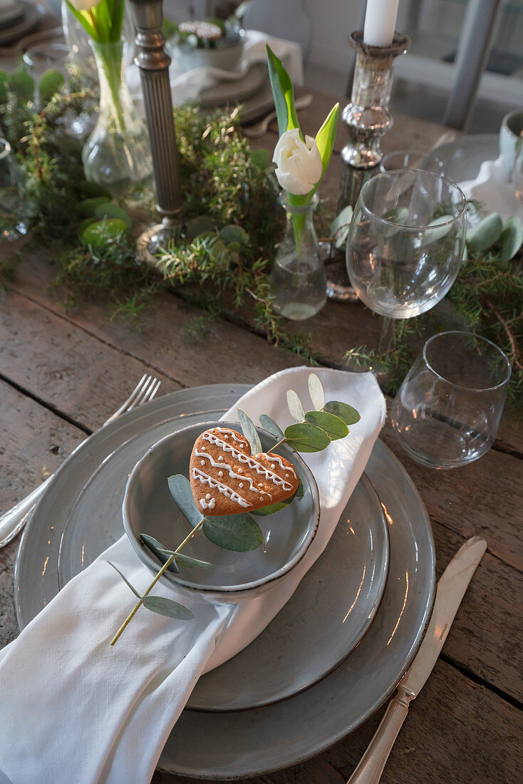 Teller mit Herz-Plätzchen und Eukalyptuszweig auf gedecktem Tisch