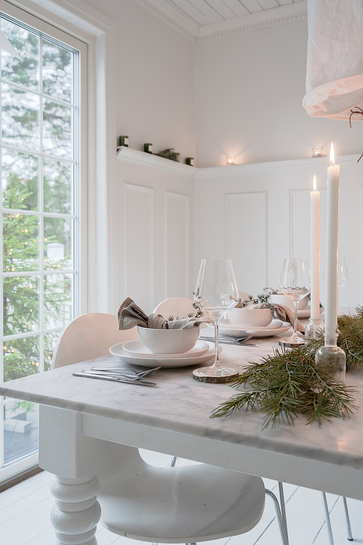 Set table in white dining room decorated for Christmas