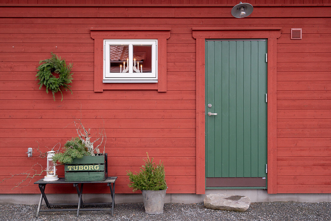 Falu-red Swedish house with green wooden door and simple winter decorations