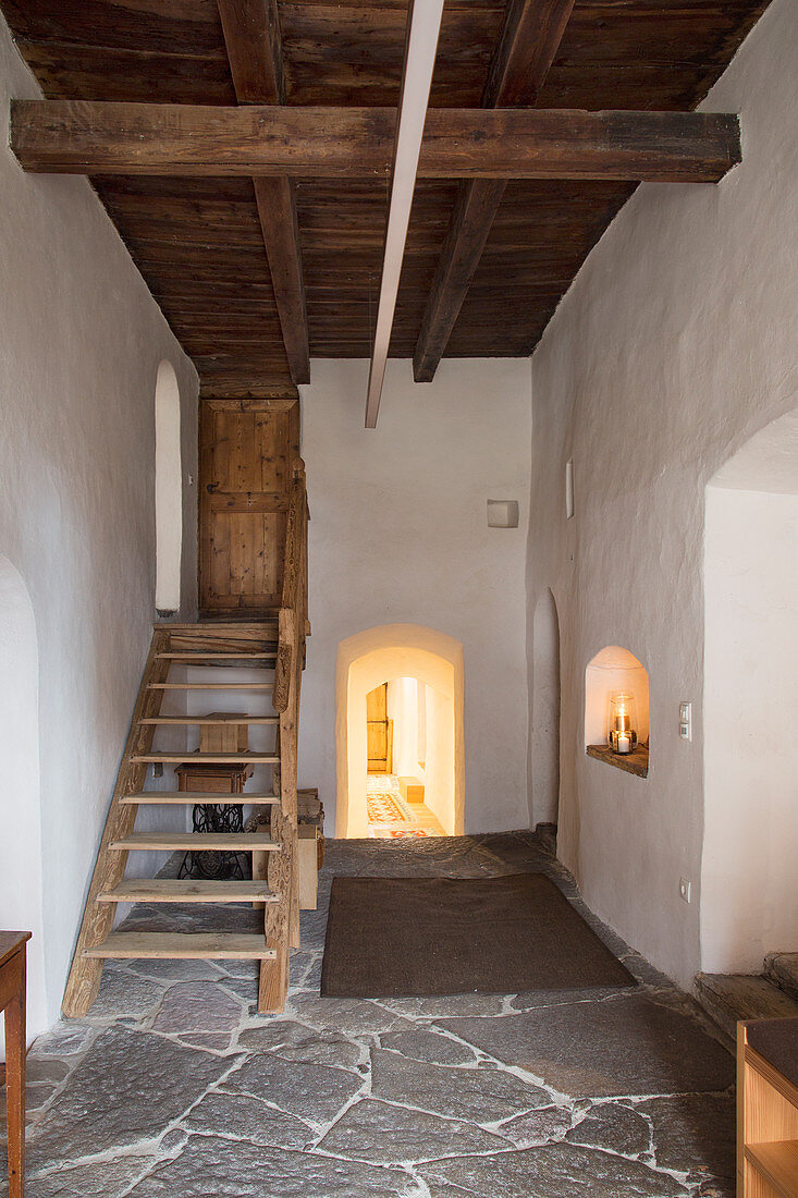 Holztreppe im Flur mit Natursteinboden im rustikalen Bauernhaus