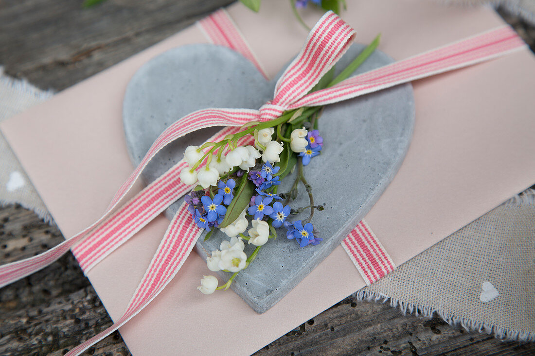 Greetings card decorated with ribbon, lily-of-the-valley and forget-me-nots on love-heart