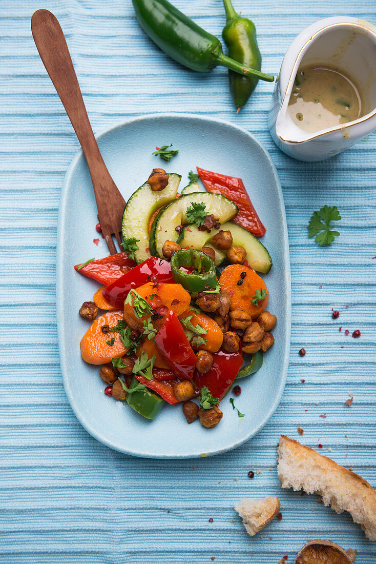 Warm salad made from roasted carrots, peppers, chilli peppers, cucumber and roasted chickpeas