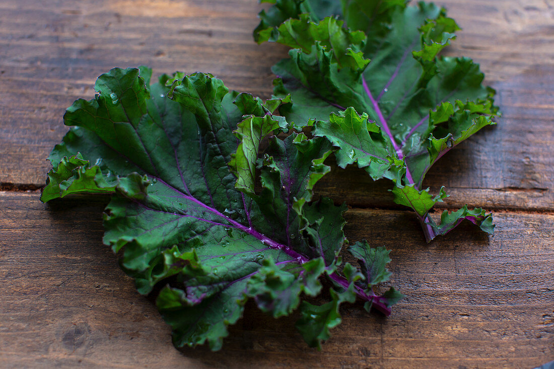 Two kale leaves on wooden background