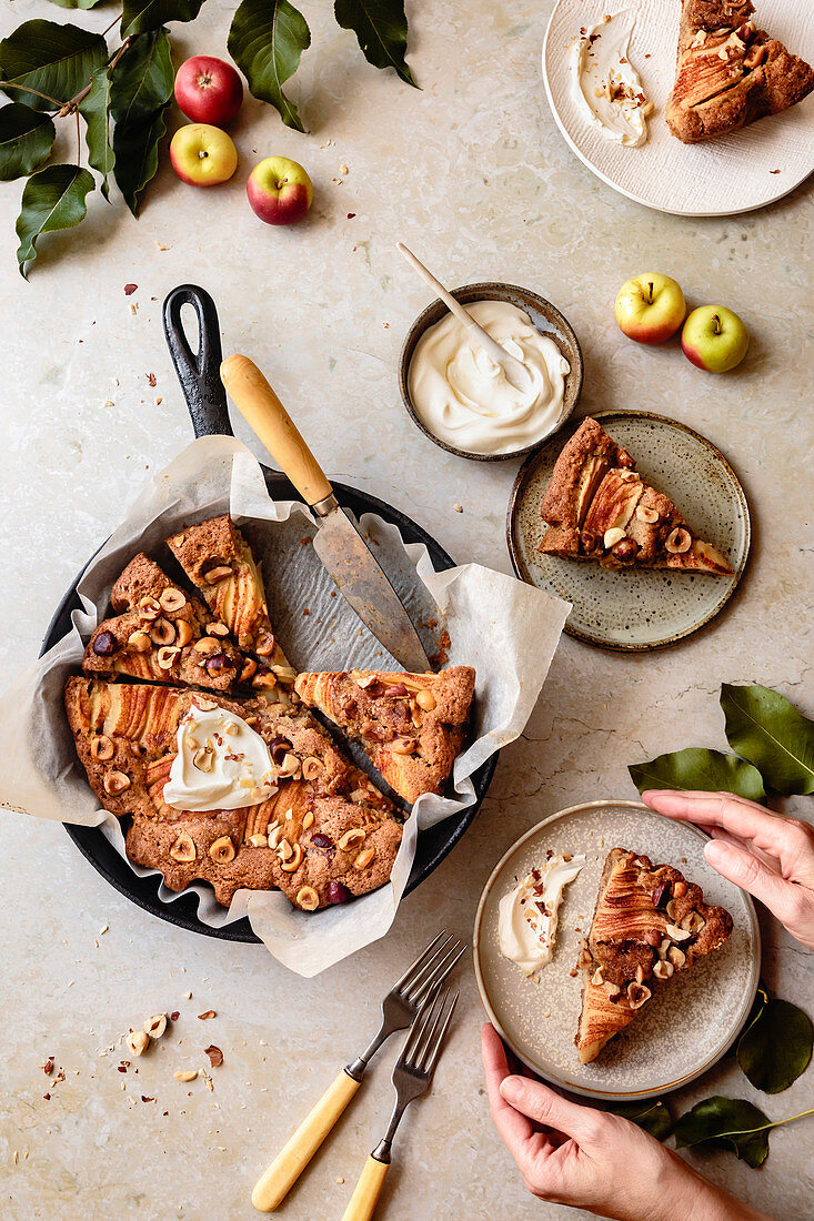 Apple hazelnut skillet cake cut into slices and served on ceramic plates.