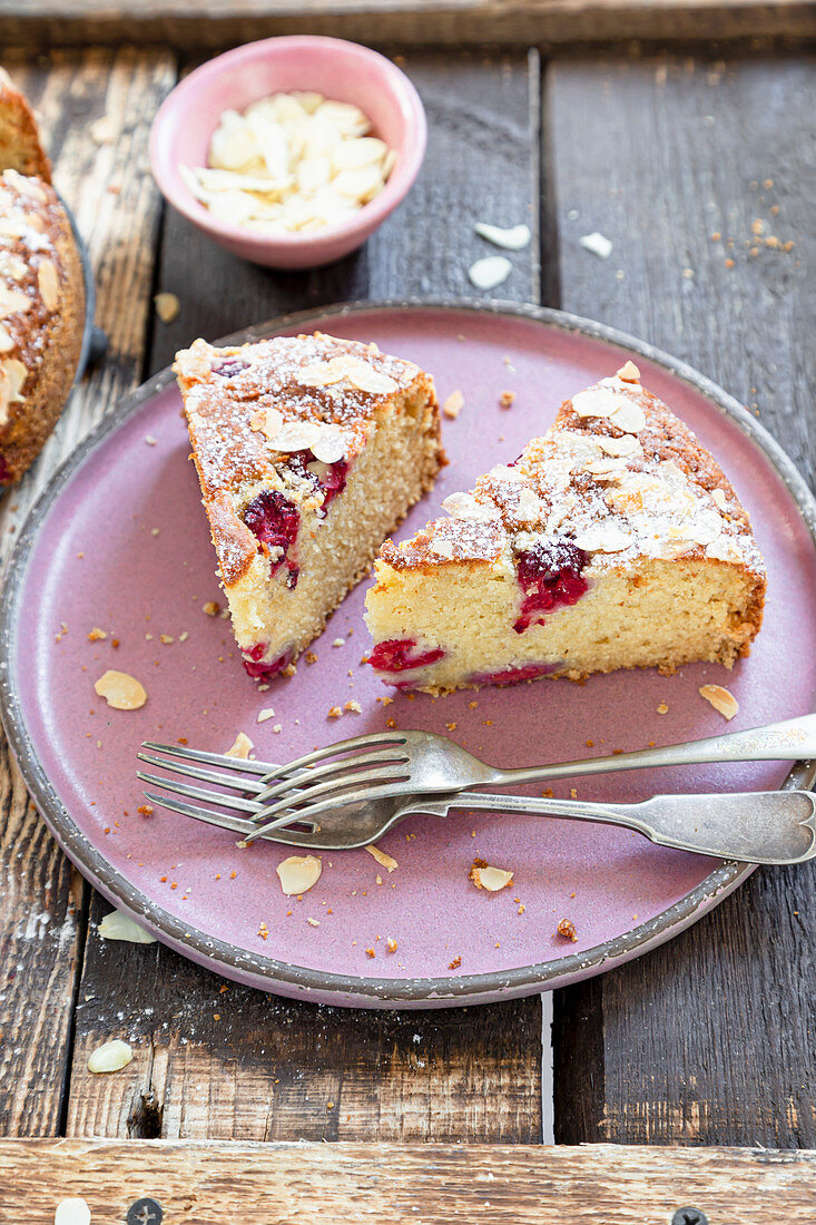 Ricotta cake with rasberries served on pink plate and wooden background.