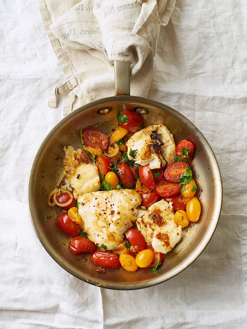 Gebratener weißer Fisch mit Kirschtomaten und Zitronenschale