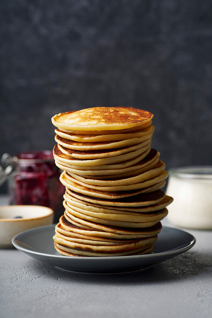 A stack of pancakes with jam and butter