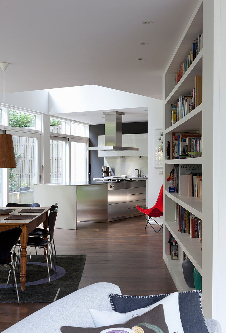 Bookcase, dining area and kitchen in open-plan interior