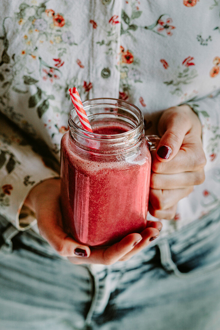 Hand hält Glaskrug mit Erdbeersmoothie