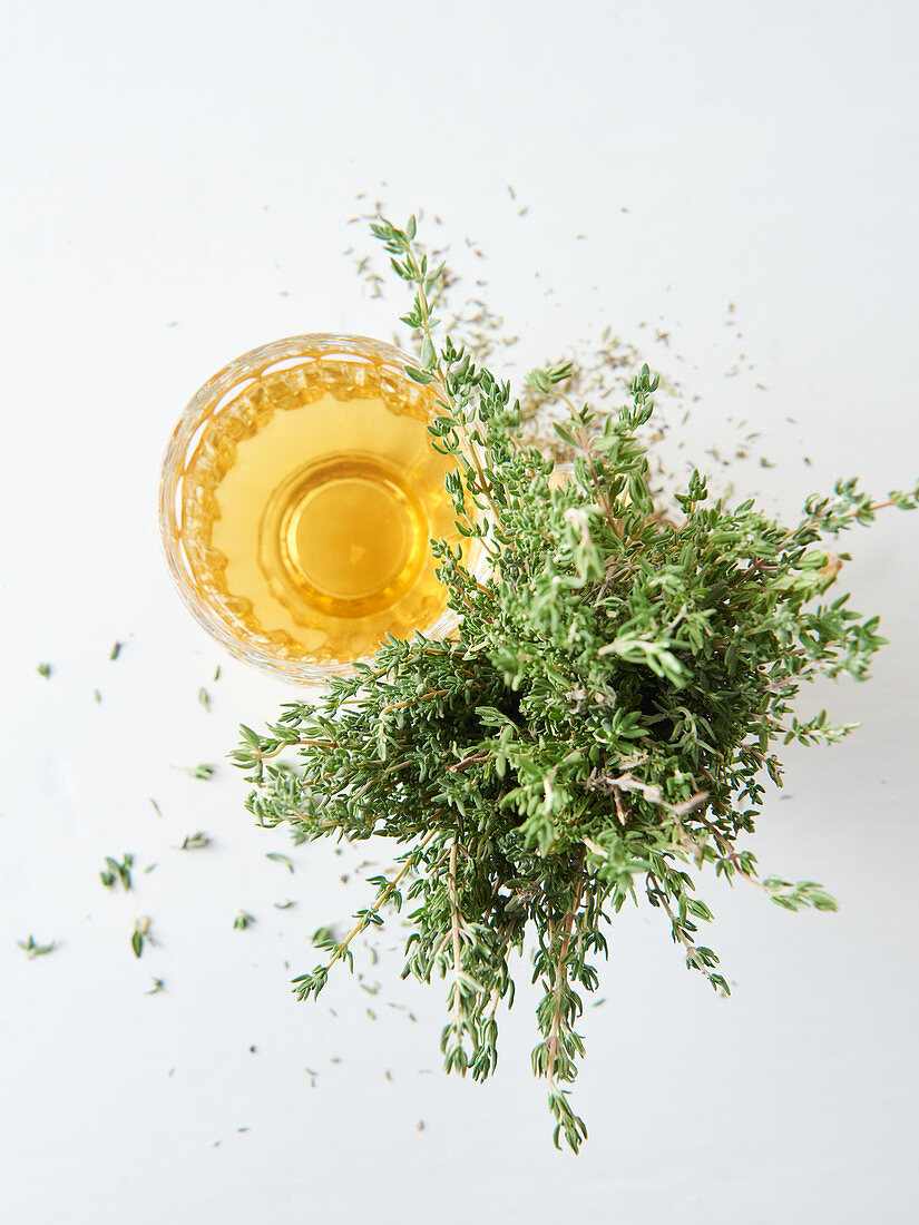 Thyme tea in a glass next to fresh thyme