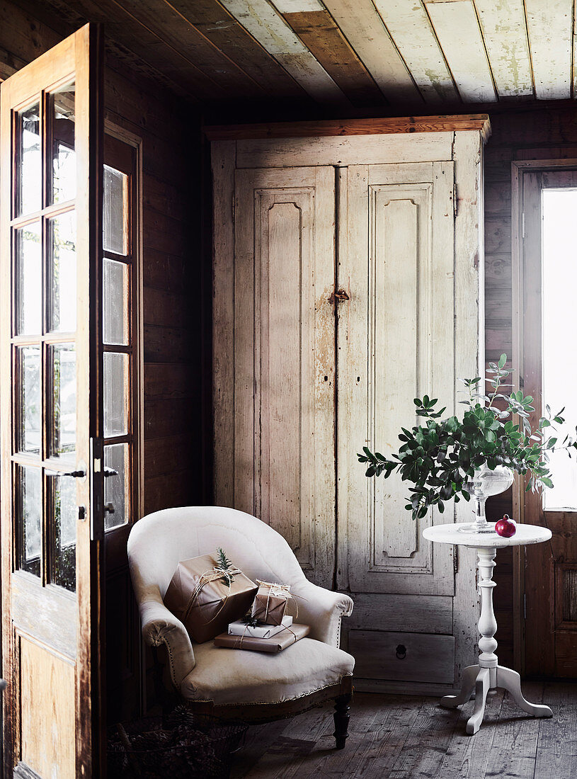 Armchair and round side table in front of wooden cupboard