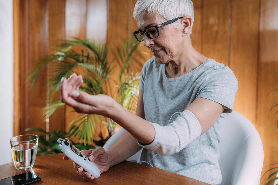 Senior woman doing elbow physical therapy with TENS