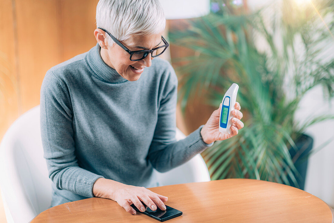 Senior woman recording body temperature