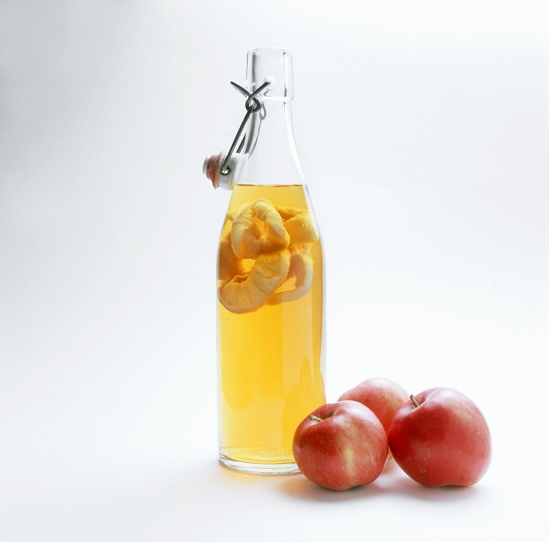 Bottle of apple vinegar and three apples