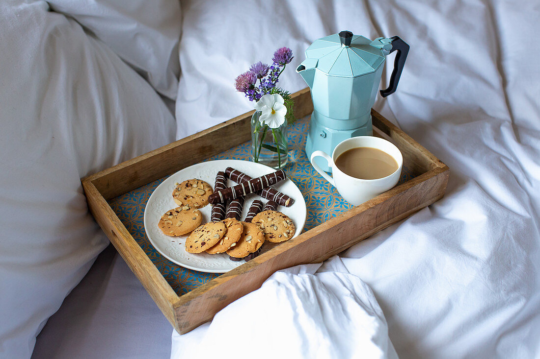 Frühstückstablett mit Plätzchen und Kaffee im Bett