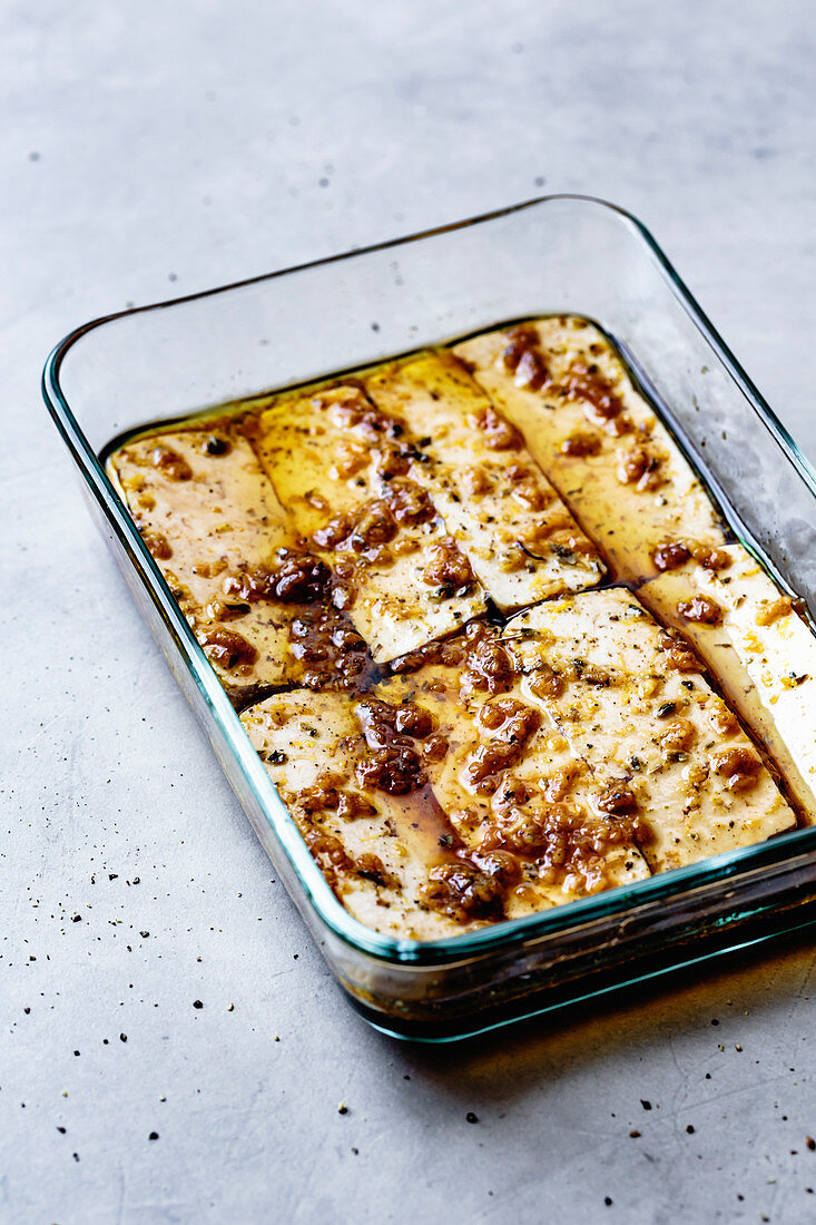 Rows of marinated tofu in a glass dish