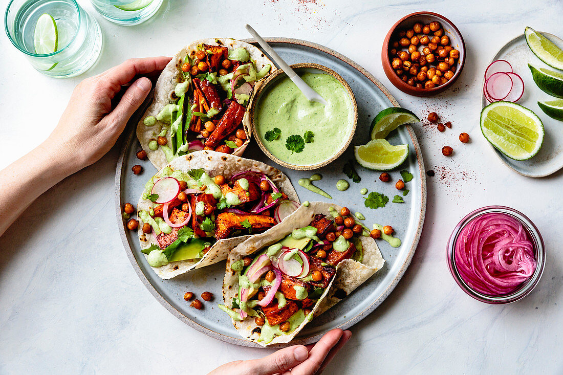 Sweet potato chickpea tacos with cilantro crema on a hand held plate