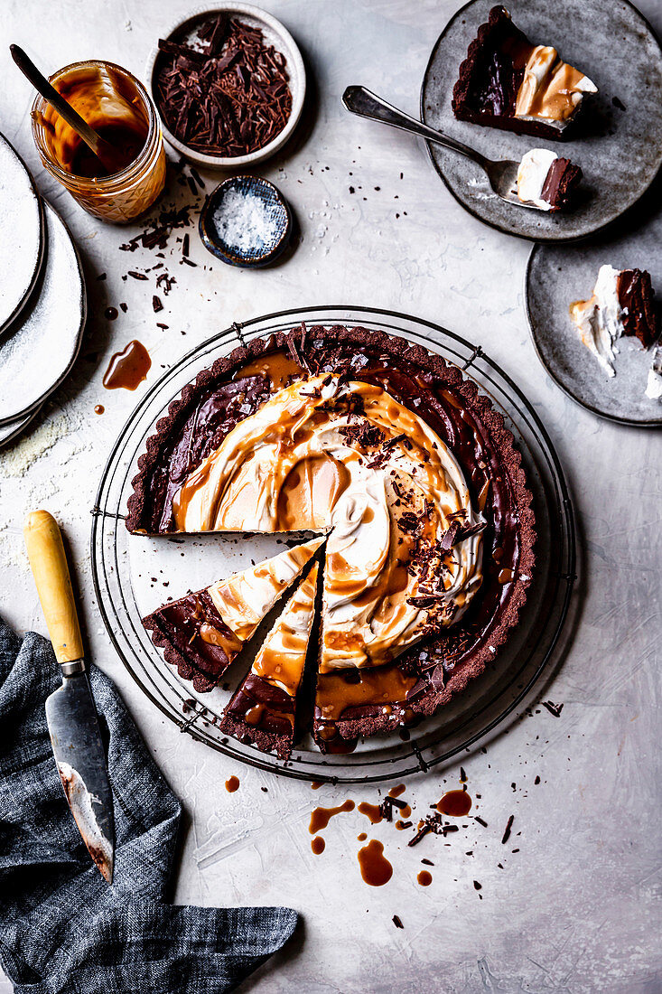 Chocolate caramel tart with slices served on plates.