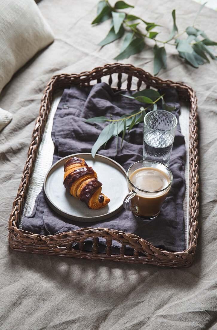 Frühstück im Bett mit Croissant und Kaffee auf Tablett