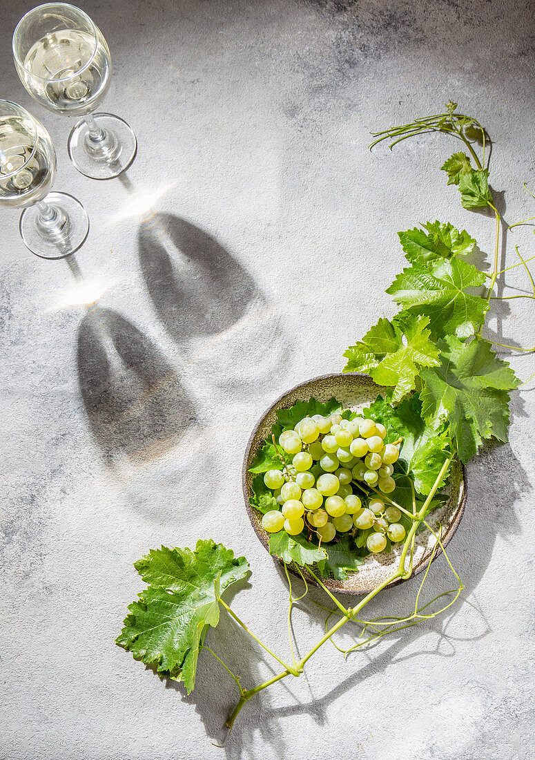 Stillleben mit Weingläsern, grünen Weintrauben und Weintraubenblättern