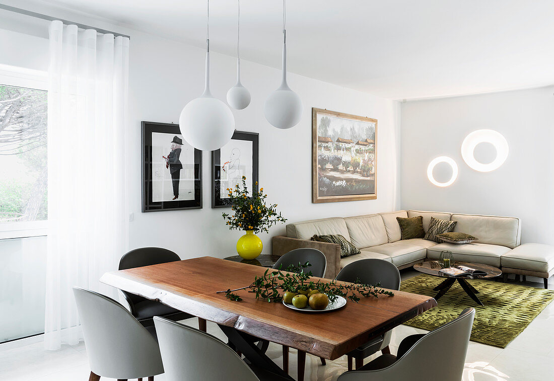 Mahogany dining table and designer shell chairs with leather sofa in background