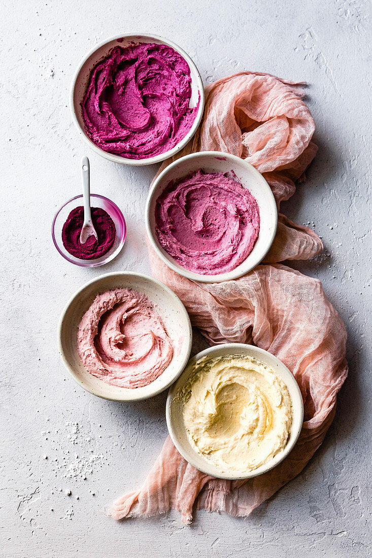 Four shades of pink frosting in bowls.