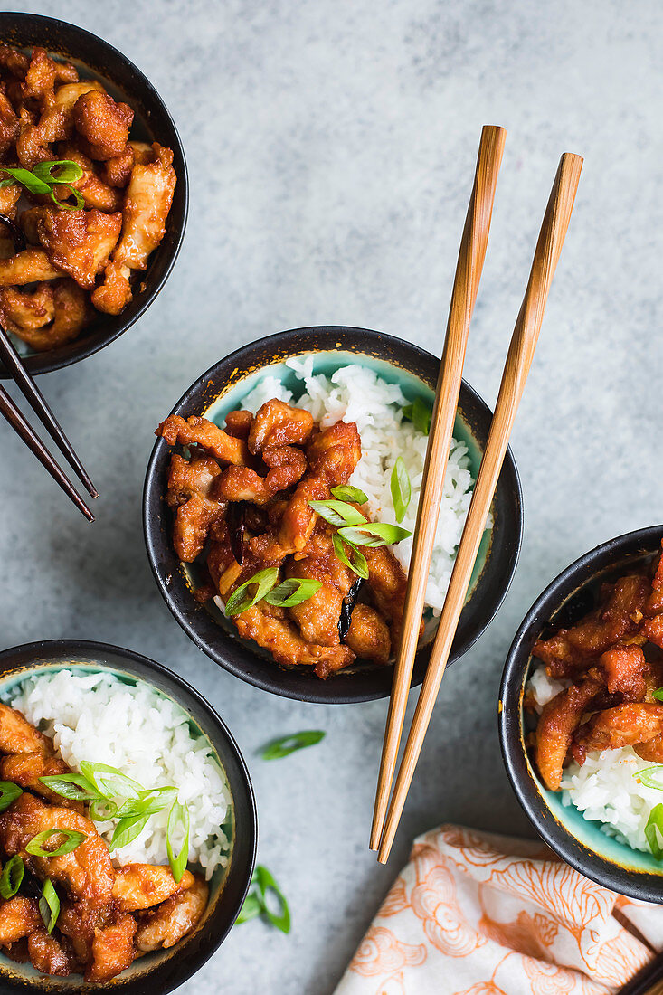 Asian style chicken in bowls with rice and chopsticks