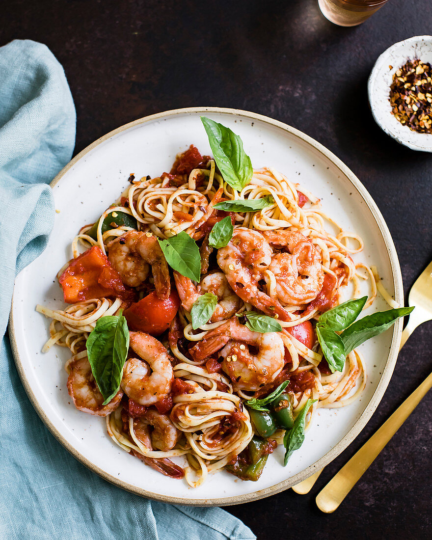 Prawns and spaghetti with basil leaves on a white plate