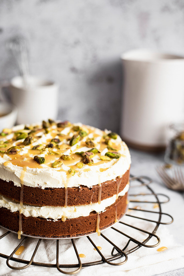 Chocolate Sandwich Cake With Vanilla Buttercream, Drizzled In Caramel And Sprinkled With Pistachios