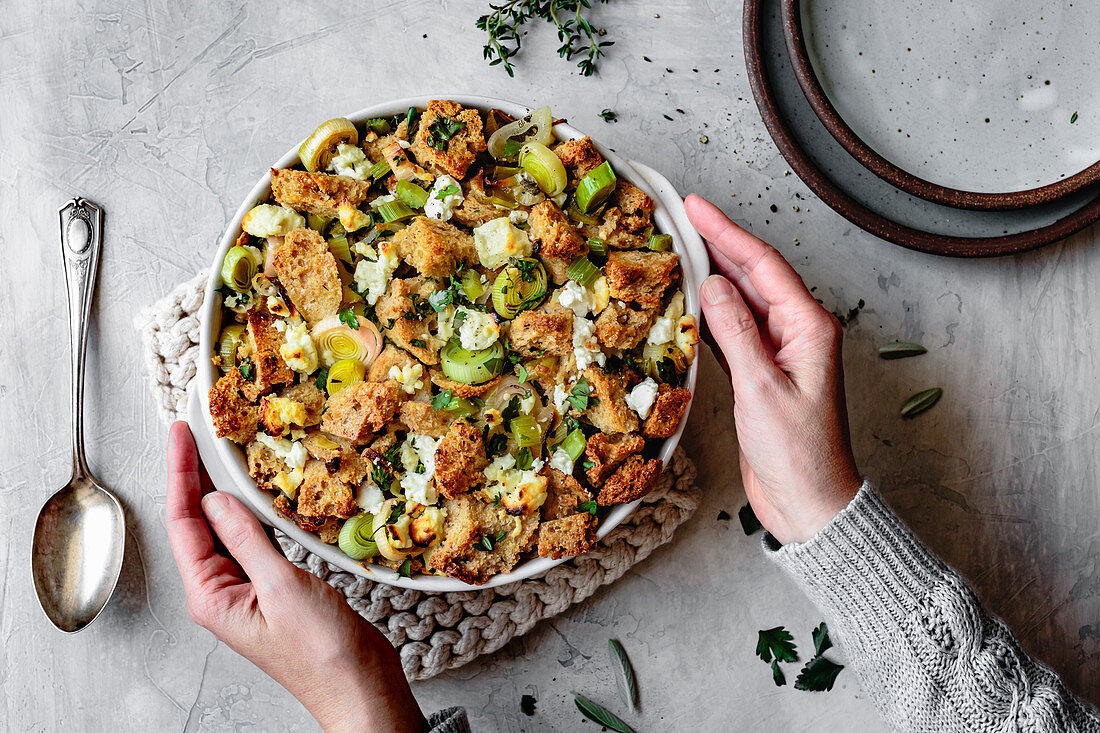 Prepared gluten free stuffing with leeks and goat cheese in a hand held baking dish.