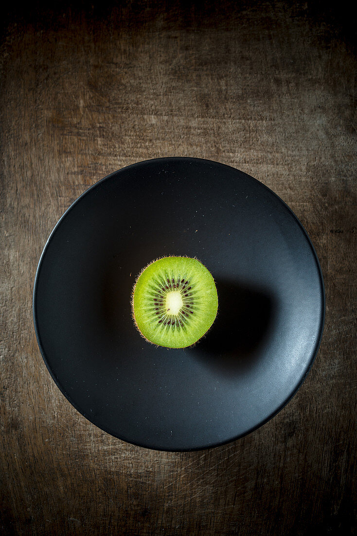 Kiwihälfte auf schwarzem Teller