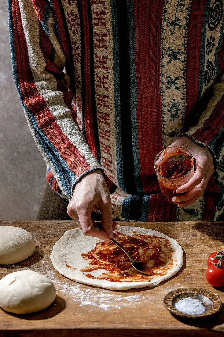 Pizza zubereiten: Teig mit Tomatensauce bestreichen