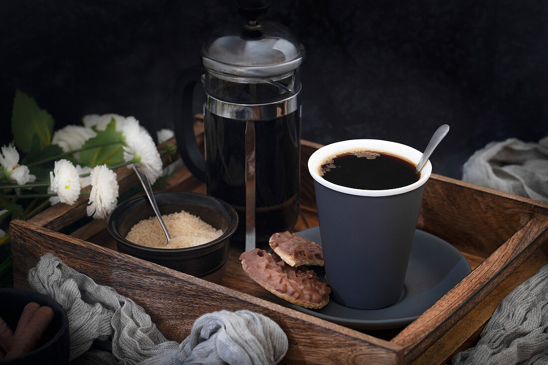 Schwarzer Kaffee serviert mit Schokoladenplätzchen auf Holztablett
